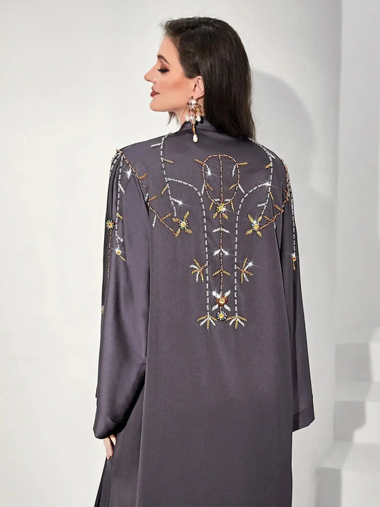 Femme portant un manteau gris avec broderies florales et sequins brillants, vue de dos