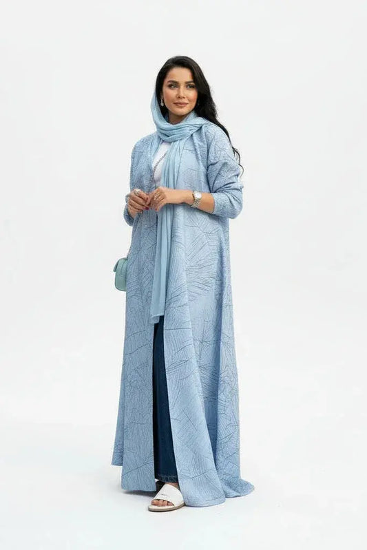 Femme élégante portant un abaya bleu clair avec motifs, foulard assorti et accessoires argentés