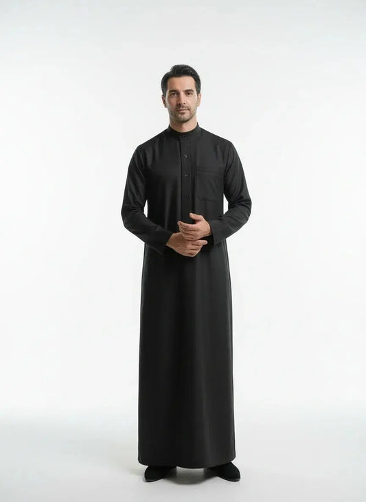 Homme portant une thobe noire traditionnelle avec col montant et manche longue sur fond blanc