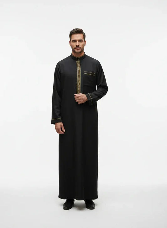 Homme portant une thobe noire avec broderies dorées, fond blanc minimaliste