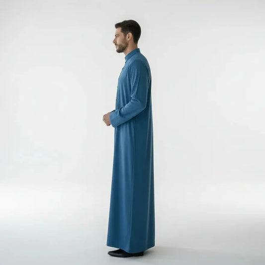 Homme portant une thobe bleue longue élégante sur fond blanc, chaussures noires