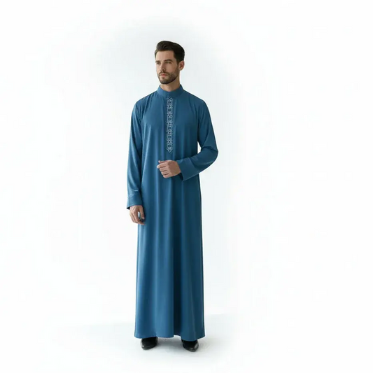 Homme portant une robe traditionnelle bleu avec broderie blanche sur col montant, fond blanc