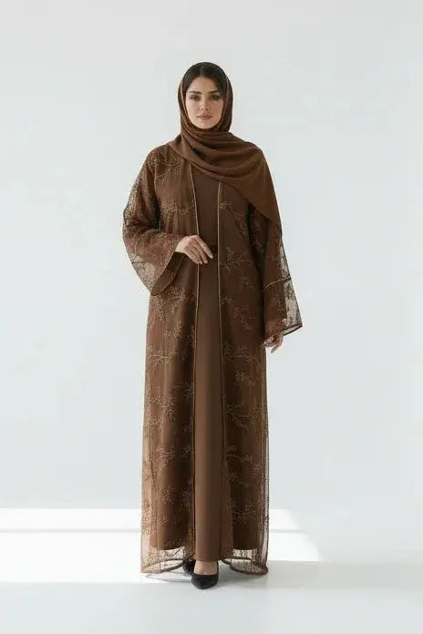 Femme en abaya marron avec motifs floraux et hijab assorti, fond blanc minimaliste