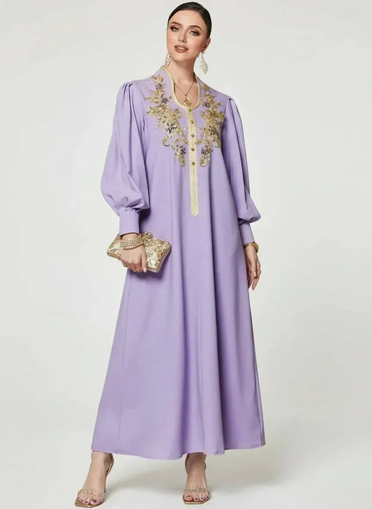 Femme en robe longue violette avec broderies dorées, tenant une pochette dorée élégante