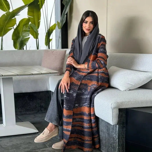 Femme élégante assise en manteau rayé orange et noir avec foulard gris, déco intérieure moderne